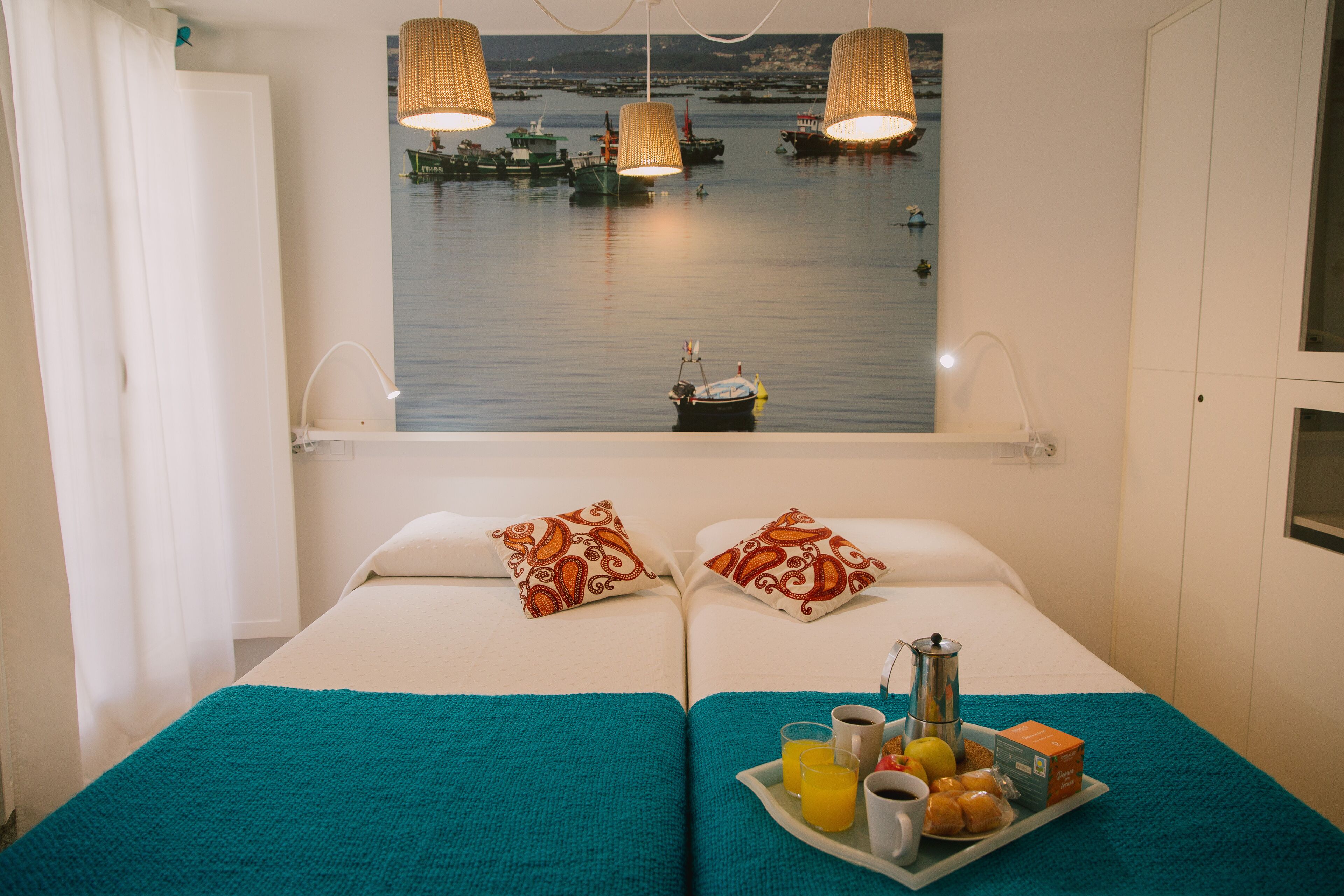 A room with a bed, a window with a view of boats, a tray with breakfast items, and a white wall.