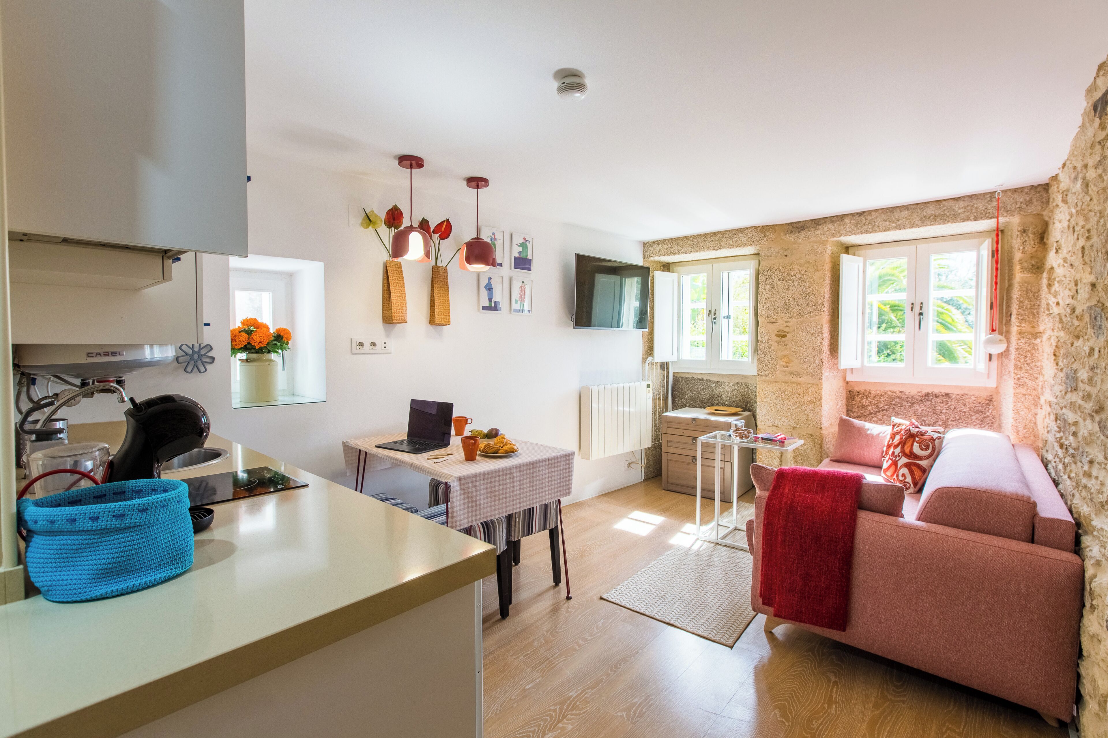 A compact living space with a kitchenette, a sofa, a dining table, and a TV.