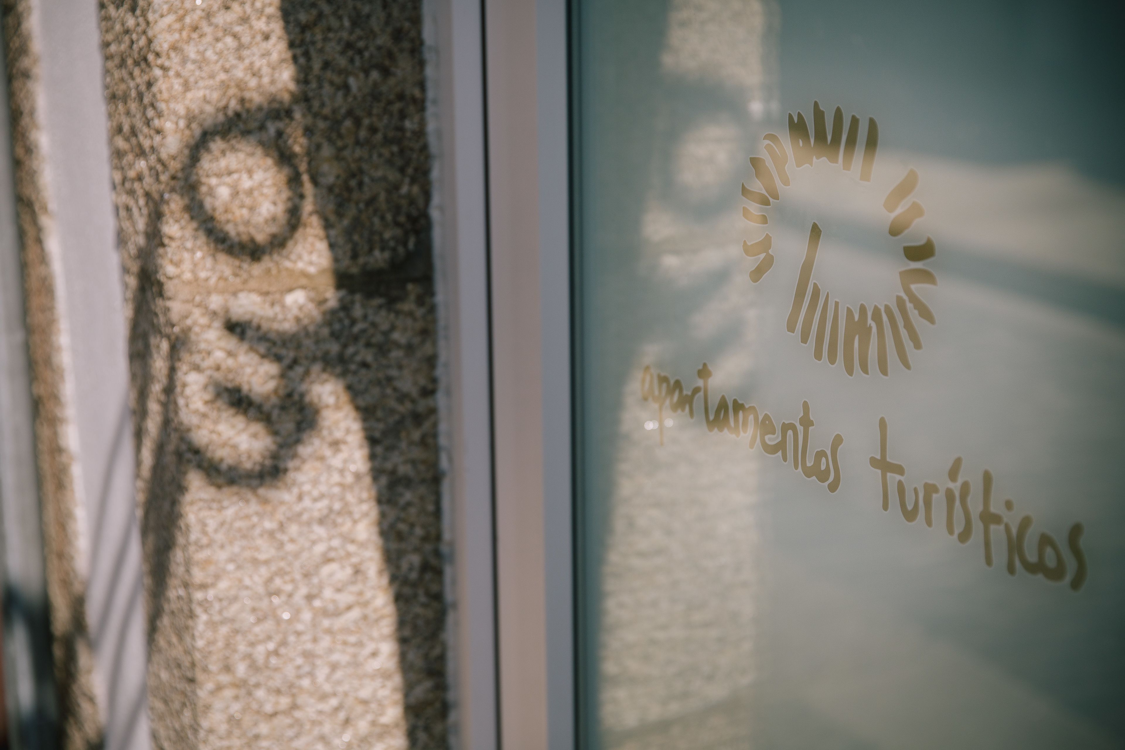 A window with a sun-like logo and the text "apartamentos turísticos".