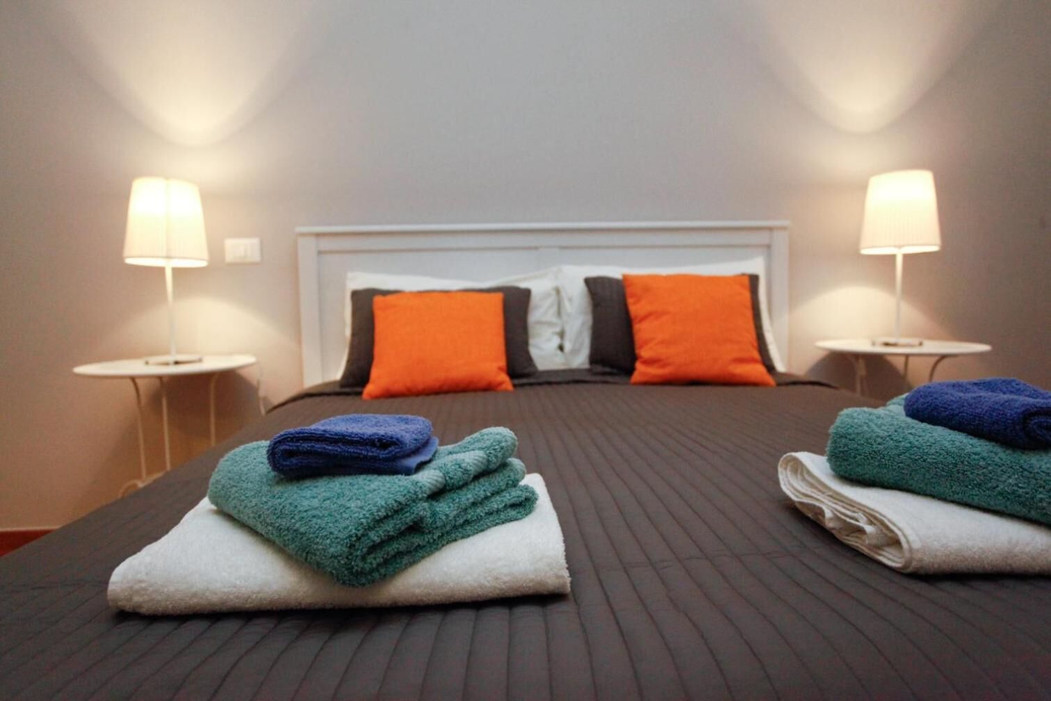 A hotel room with a large bed, two nightstands, and two lamps.