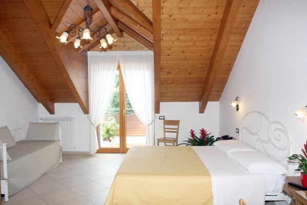 A bedroom with a bed, a chair, a desk, and a window with curtains.