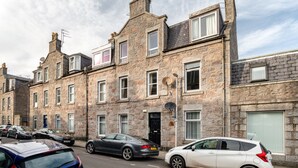 A row of stone townhouses with multiple windows and a street in front. - West Mount Apartment (Aberdeen)