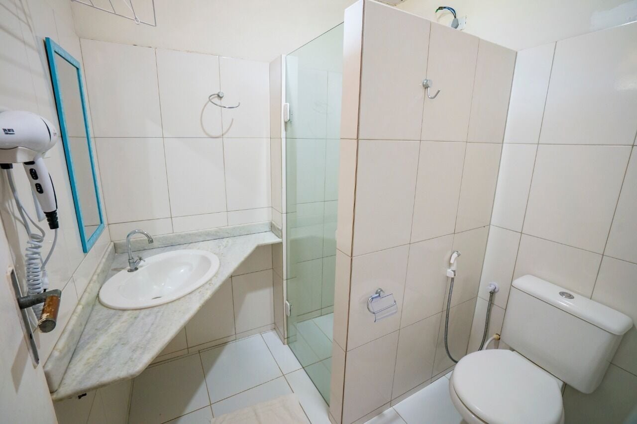 Een badkamer met wastafel, toilet en douchecabine met glazen wanden.