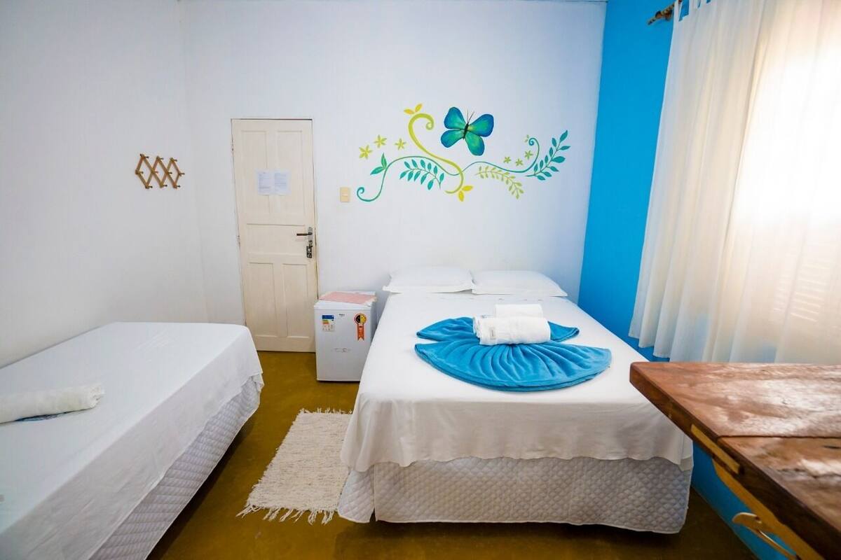 A room with a bed, a bedside table, a small desk, and a wall decoration.