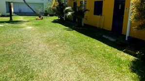 A building with a flat roof, a water tank on the roof, and a well-maintained lawn. - Pousada Sunset Boipeba (Cairu)