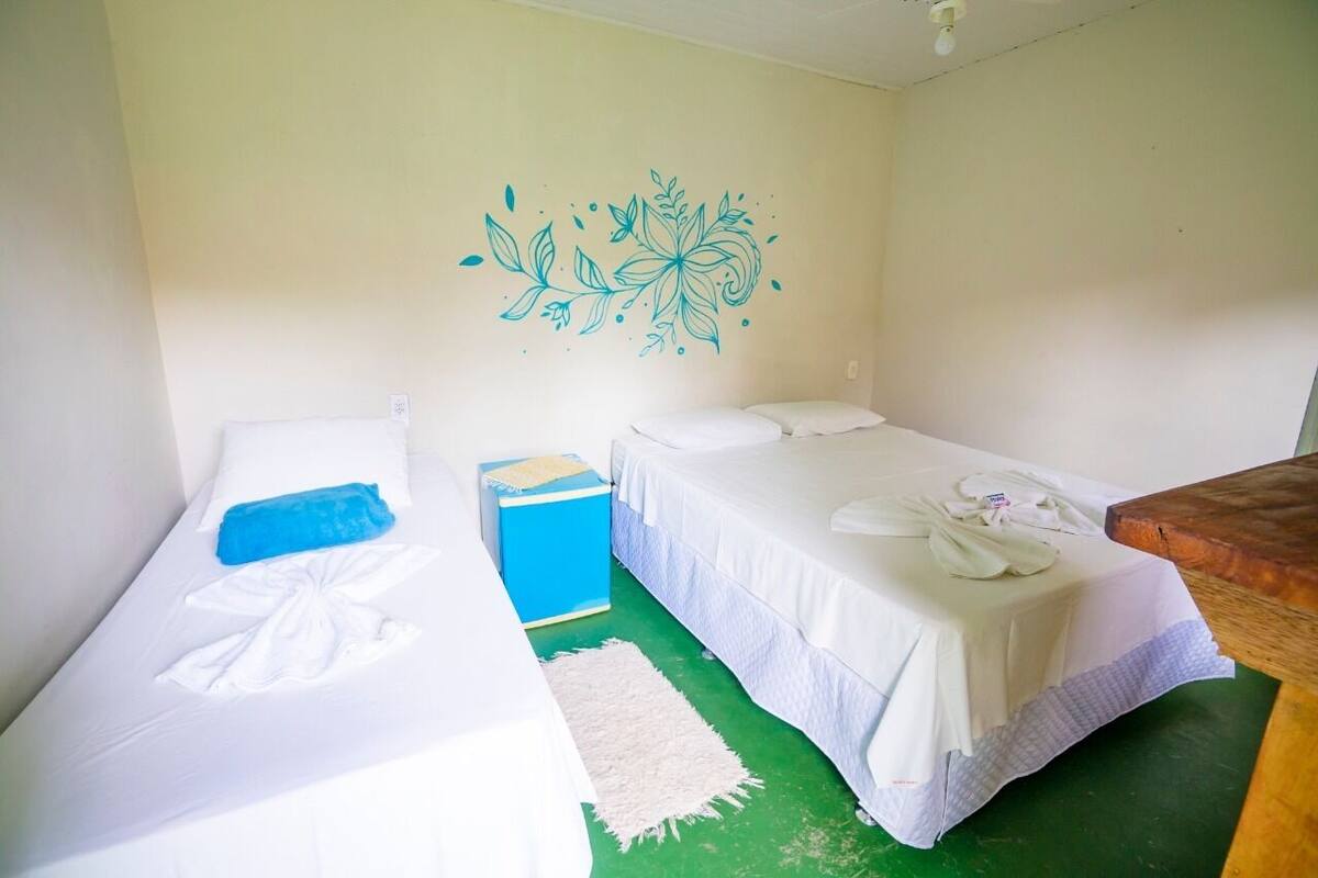 A room with two beds, a blue nightstand, a white pillow, and a decorative wall design.