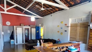 A spacious room with a high ceiling, a wooden ceiling, a bar area with stools, a sofa, and a dining table. - Pousada Sunset Boipeba (Cairu)