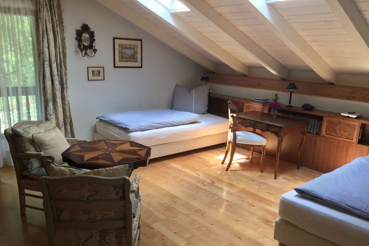 A cozy attic room with a bed, a desk, and a chair.