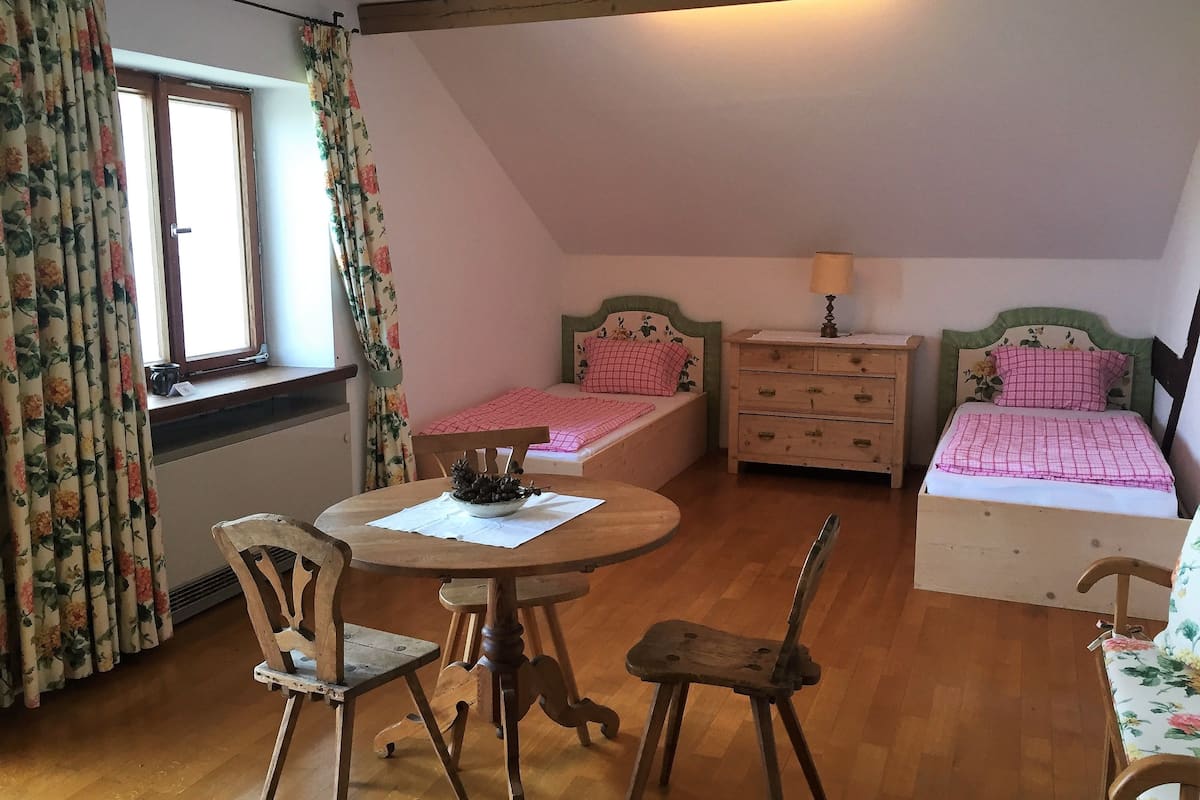 A cozy bedroom with two beds, a wooden table, and chairs.
