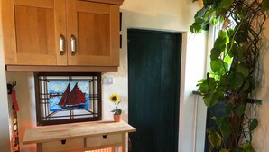 Una stanza accogliente con mobili in legno, una porta, uno scaffale con un oggetto decorativo e una pianta in vaso.