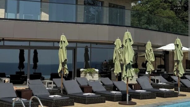 Un hôtel moderne doté d’une piscine, de chaises longues et de parasols.