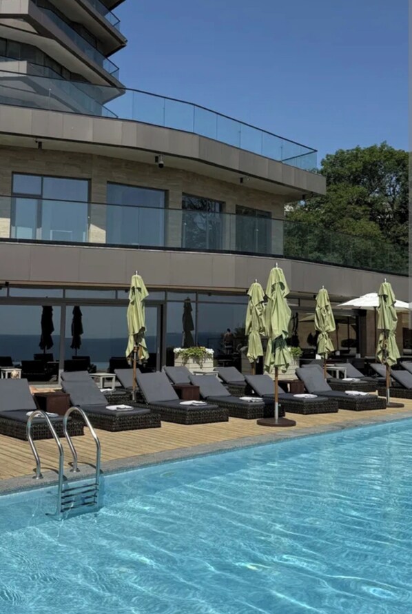 A modern hotel with a pool area, sun loungers, and umbrellas. - Apartment Greenwood near Sea (Odesa)