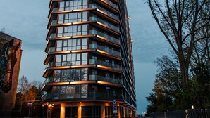 Un immeuble moderne à plusieurs étages, doté d’une façade en verre et d’une série de balcons.