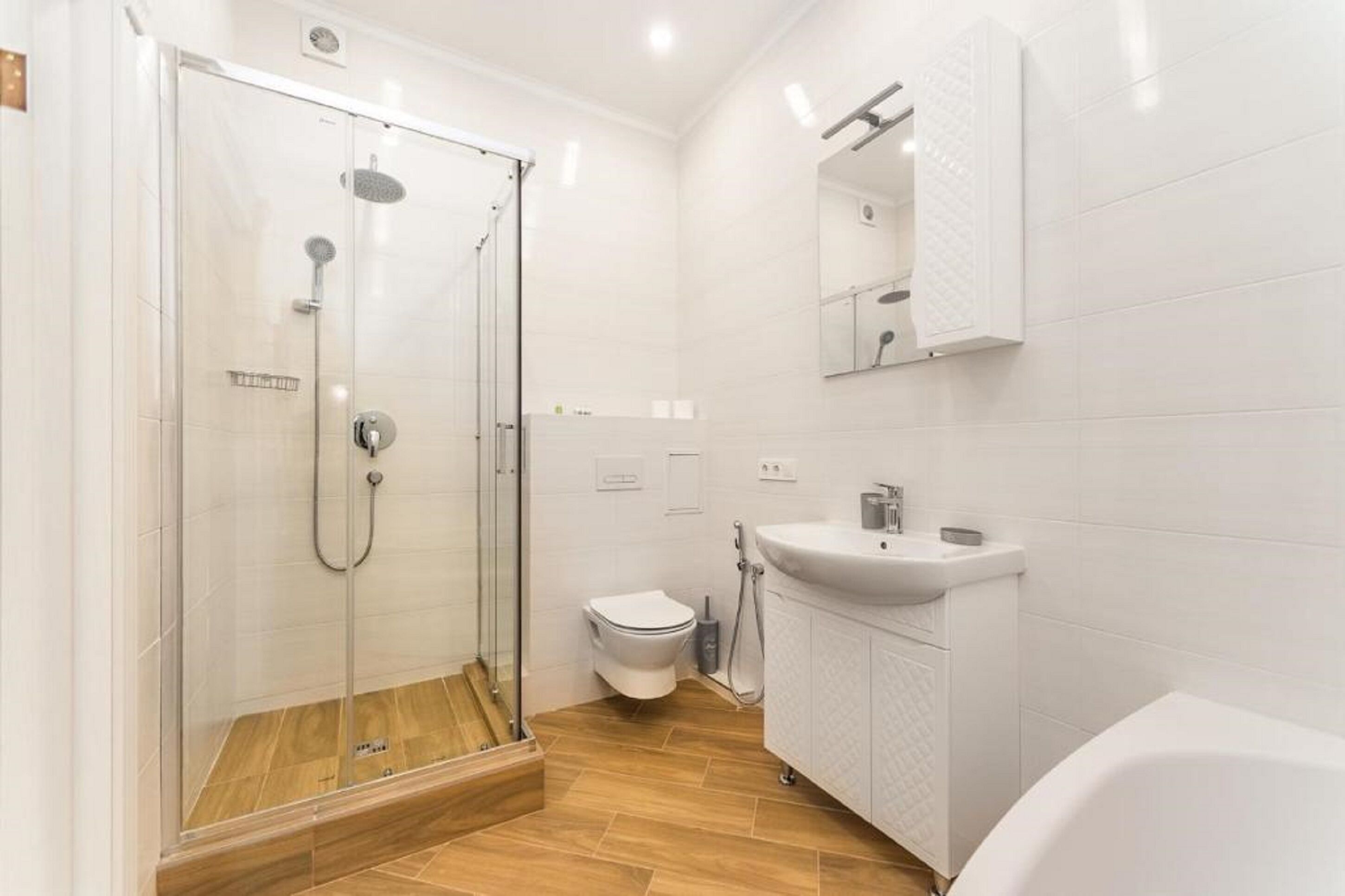 A modern bathroom with a glass-enclosed shower, a white toilet, a sink, and a mirror above the sink.