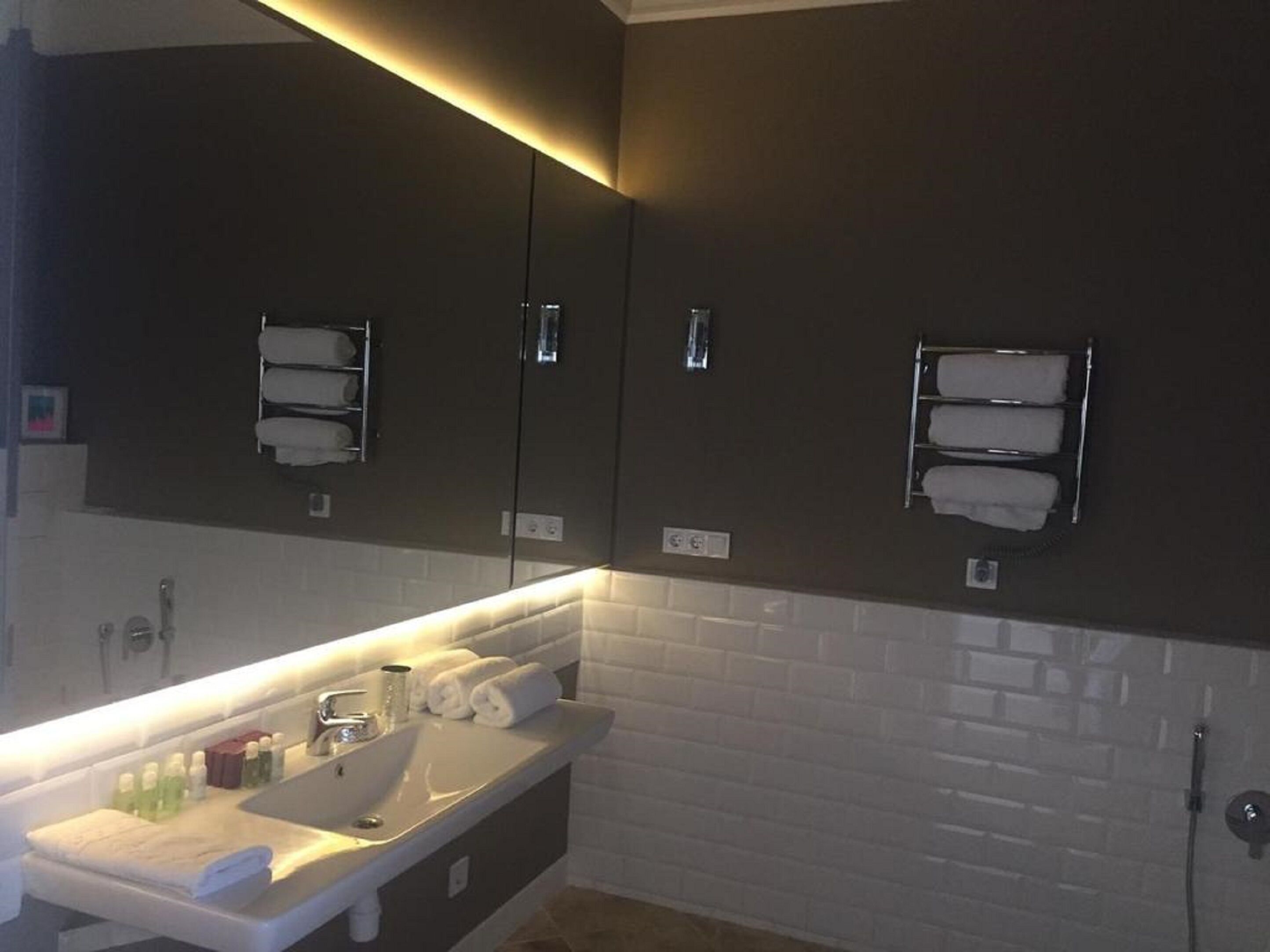 A modern bathroom with a white sink, dark cabinets, and a towel rack.