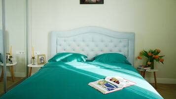 A bedroom with a bed, a bedside table, a mirror, and a framed picture on the wall.