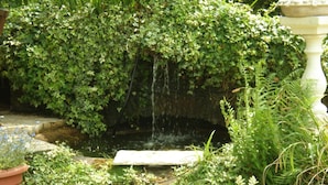 A garden with a water feature, including a stone basin and a white pedestal. - Haigs Hotel (Solihull)