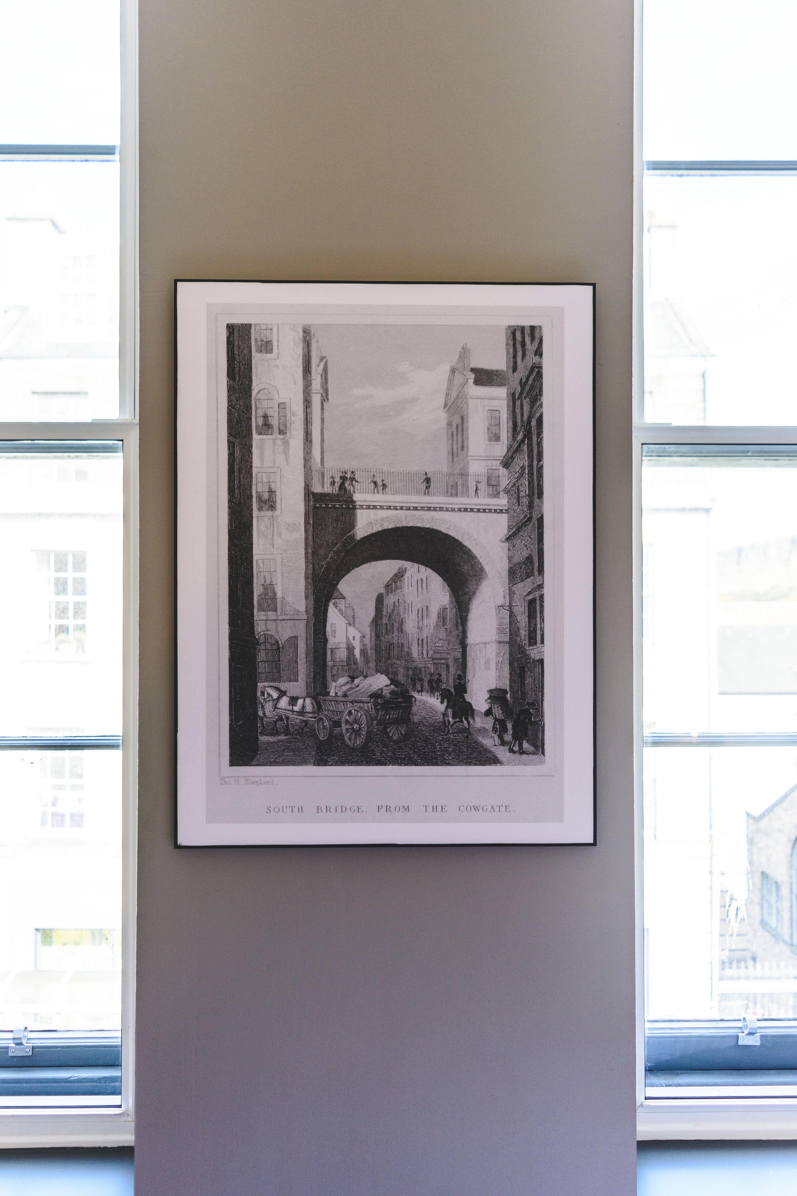 A framed black and white photograph of a street scene with an archway, titled "South Bridge, From the Cowgate."