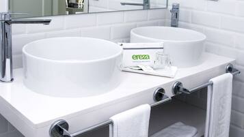 Casa de banho moderna com duas pias, um espelho e um secador de cabelo fixado na parede.
