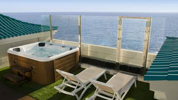 Ein Balkon mit Whirlpool, zwei Liegestühlen und Blick auf den Ozean.