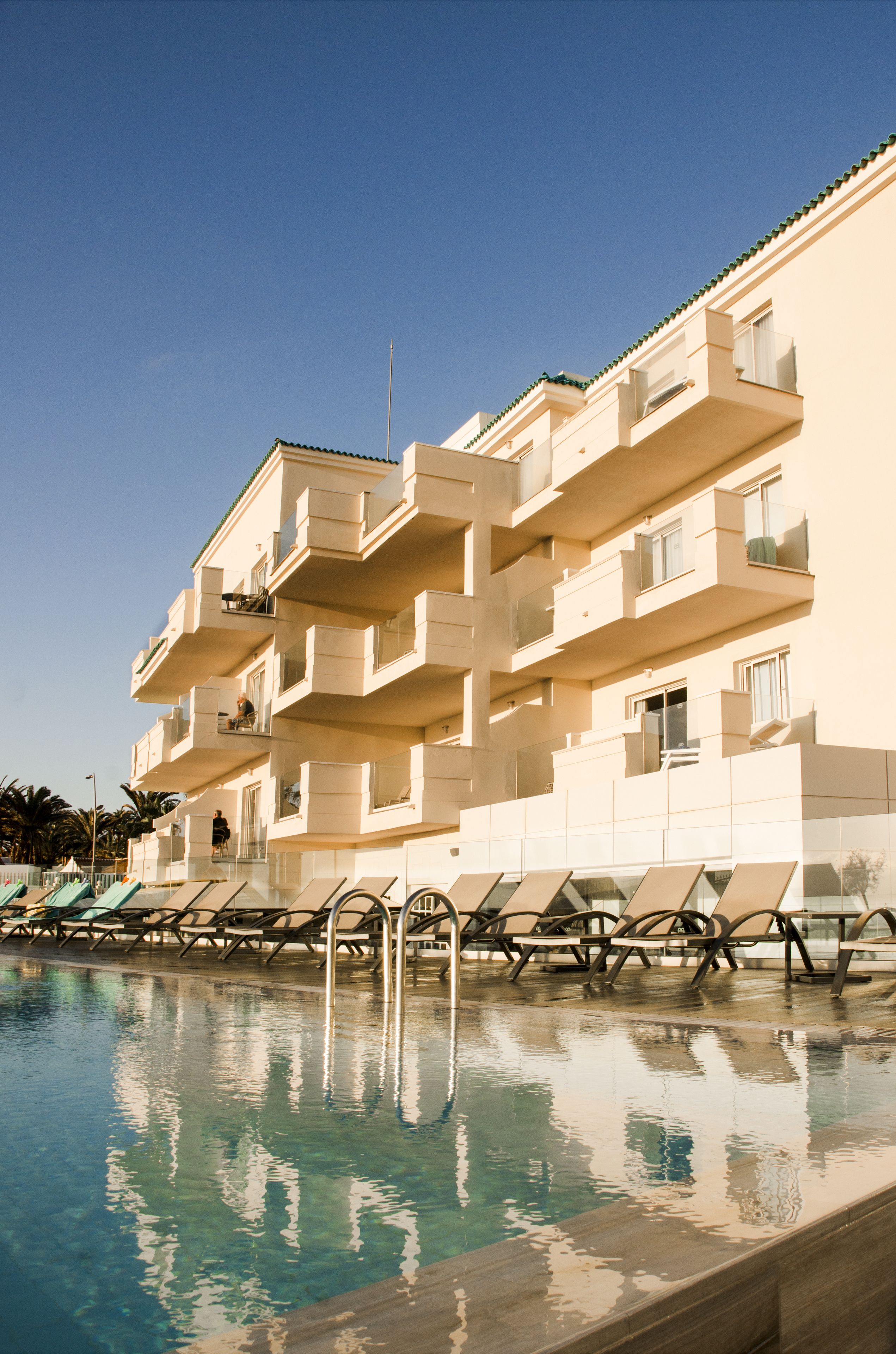 Un hôtel doté d’une piscine, de plusieurs balcons et offrant une vue sur un ciel dégagé.