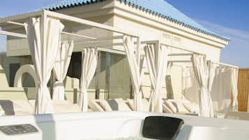 Un área de hidromasaje con zona de estar techada y una piscina.