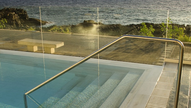 A pool with clear water, a wooden deck, and a metal railing. - Hotel Ereza Mar- Adults Only (Antigua)