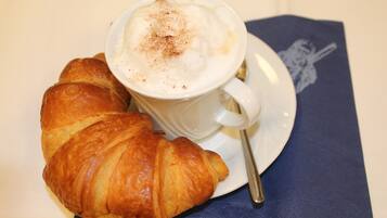 Un croissant y una taza de café sobre un platito.