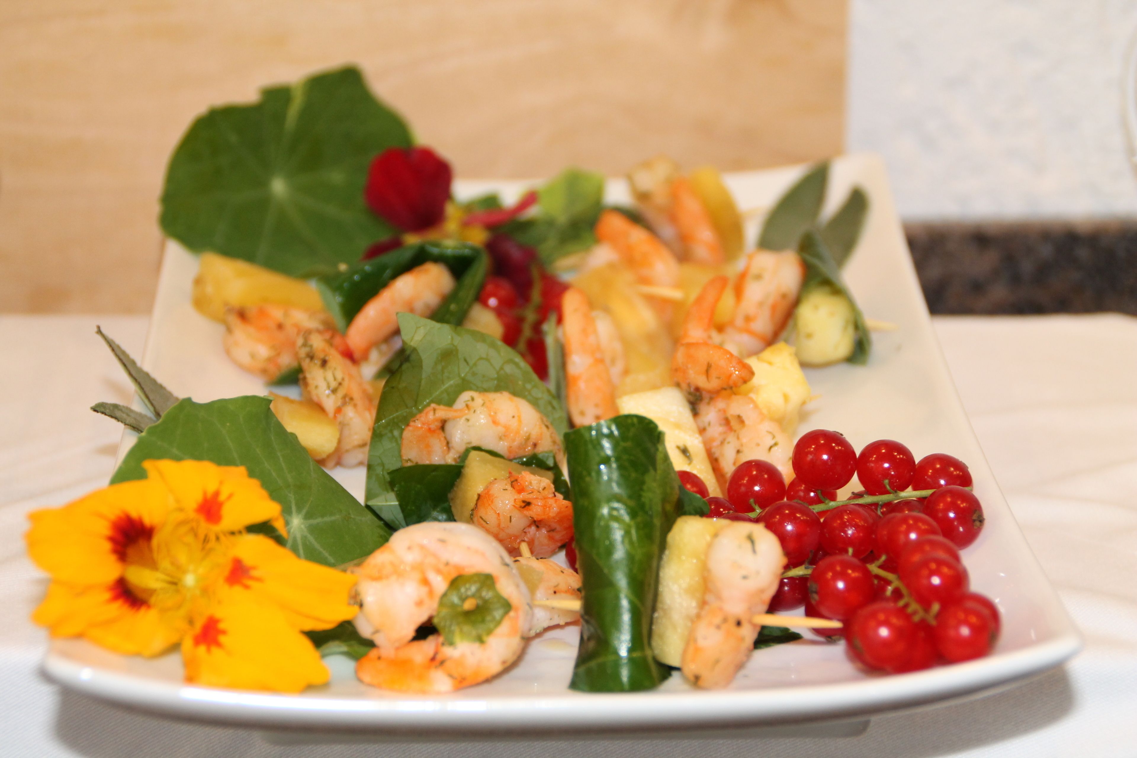 A plate of shrimp with vegetables and red berries.