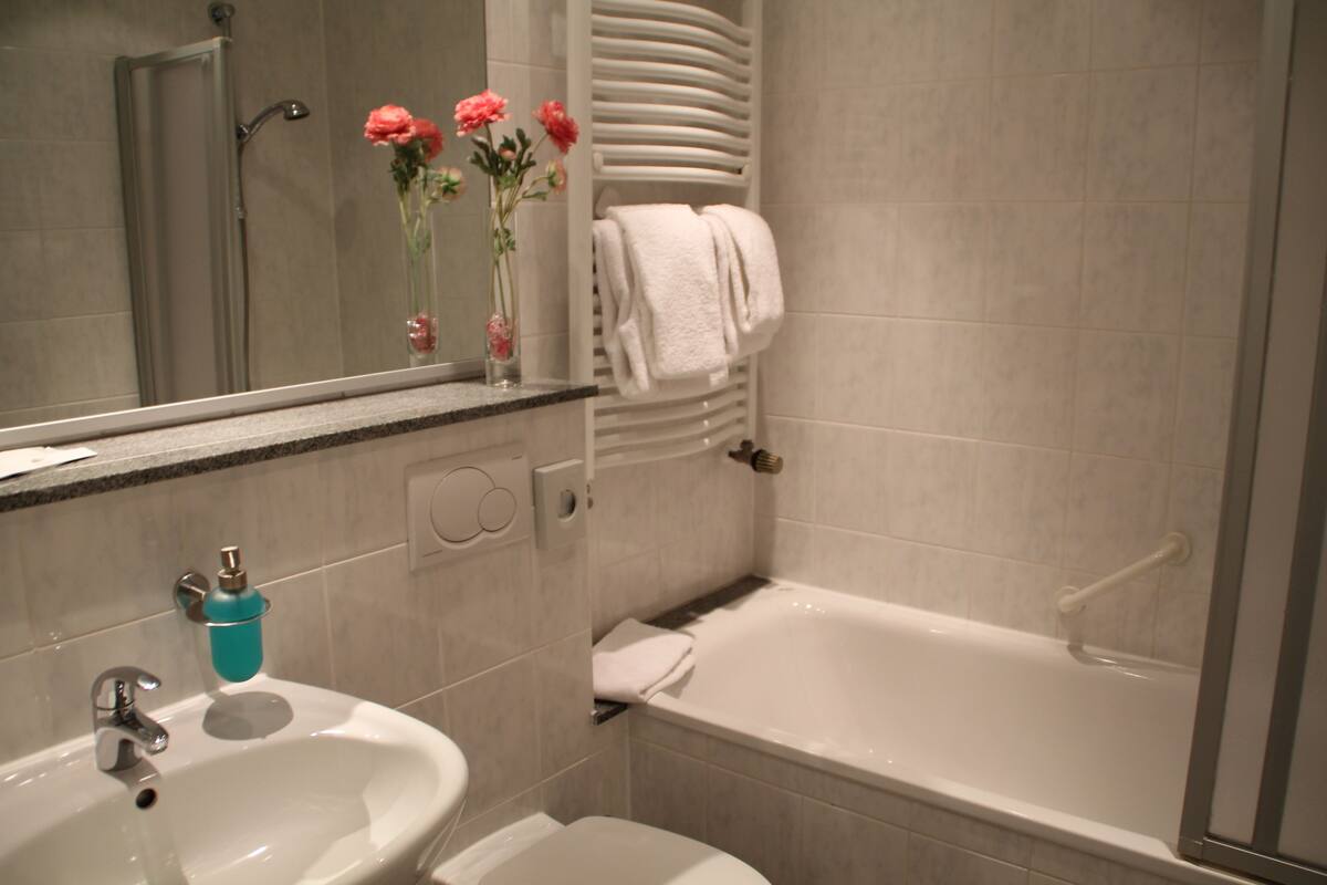 A bathroom with a sink, mirror, vanity, bathtub, and towel rack.
