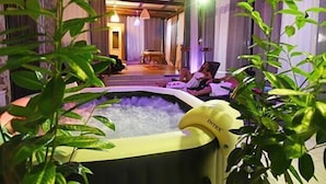 Et spaområde med jacuzzi, indeplanter og et siddeområde med mennesker.