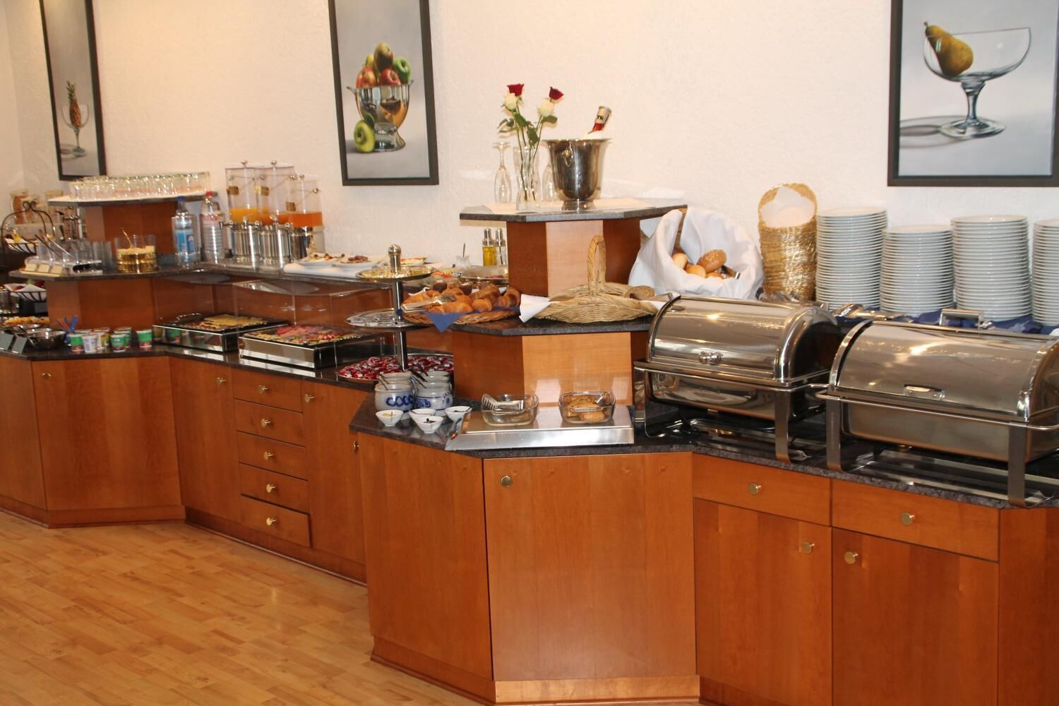 A buffet setup with various food items, a coffee station, and decorative elements like framed pictures and flowers.