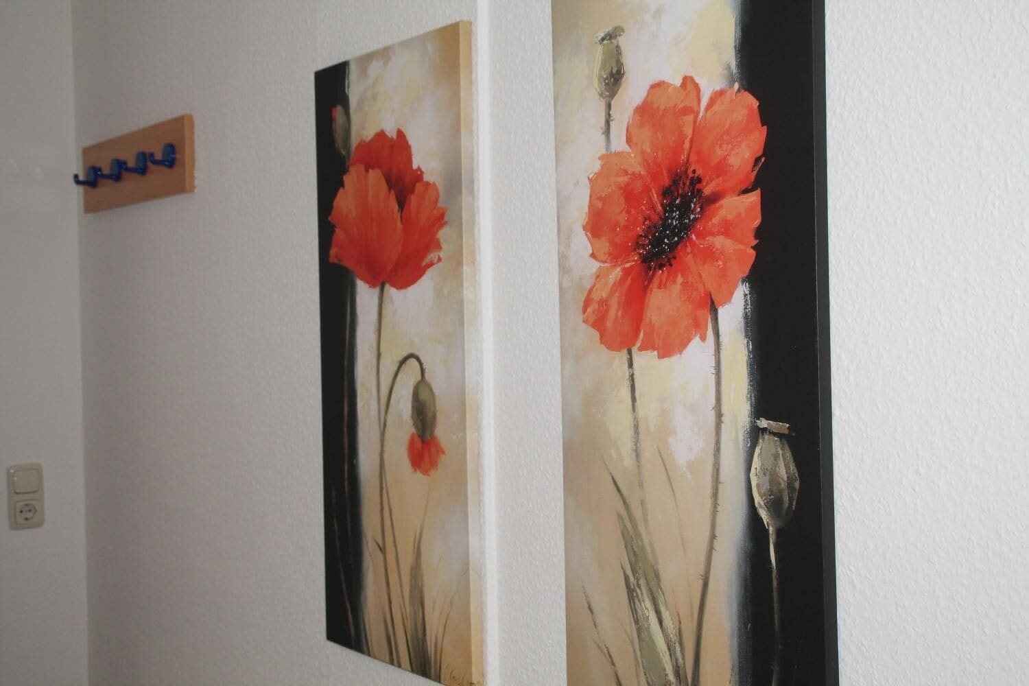 Zwei Gemälde von roten Mohnblumen an einer Wand.