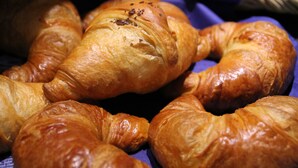 A basket of golden-brown croissants with a glossy finish, arranged on a blue cloth. - Hotel Römerhof by Trip Inn (Hanau)