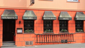 A building with signs for a steakhouse, grill, restaurant, hotel, and another establishment. - Hotel Römerhof by Trip Inn (Hanau)