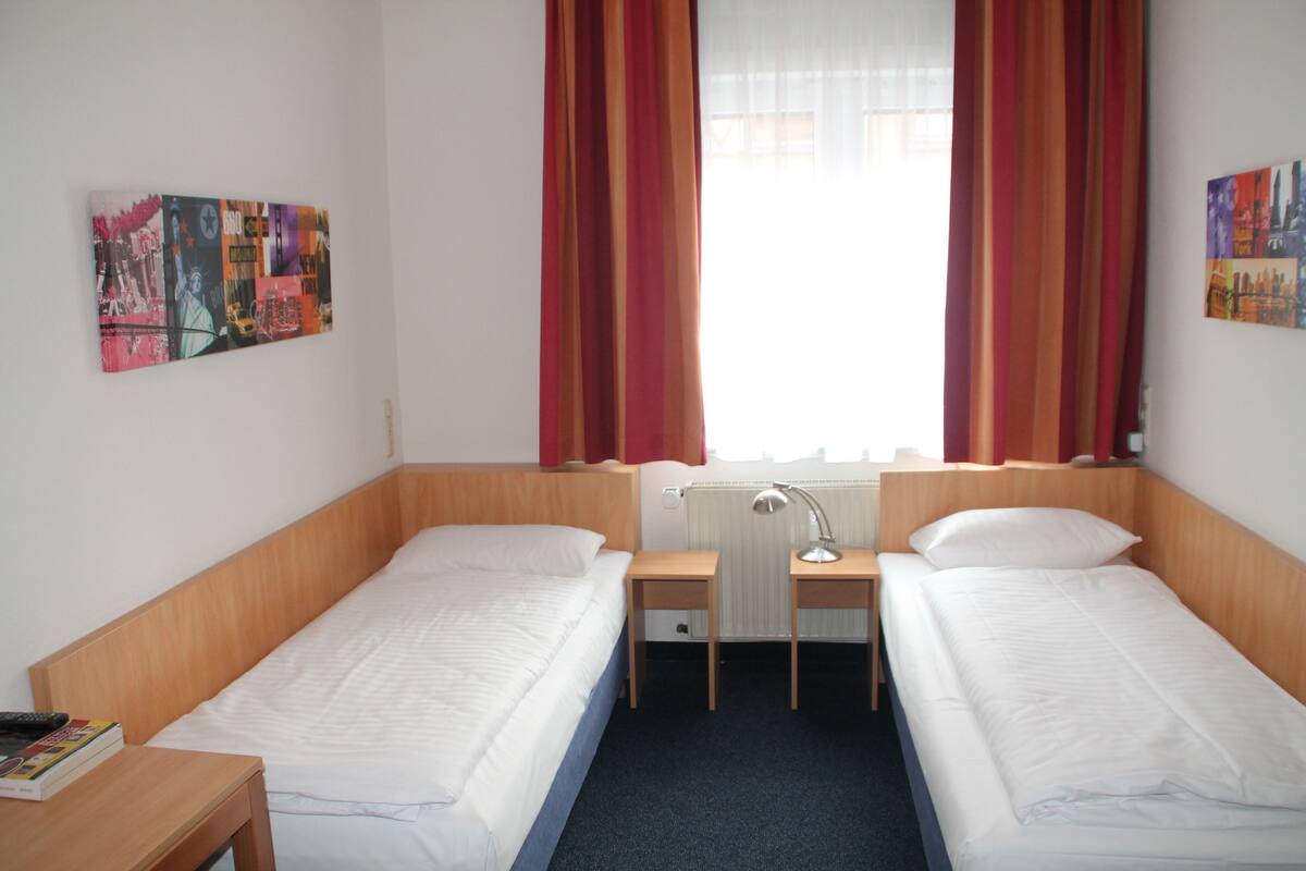 A twin room with two single beds, a desk, a chair, and a radiator.
