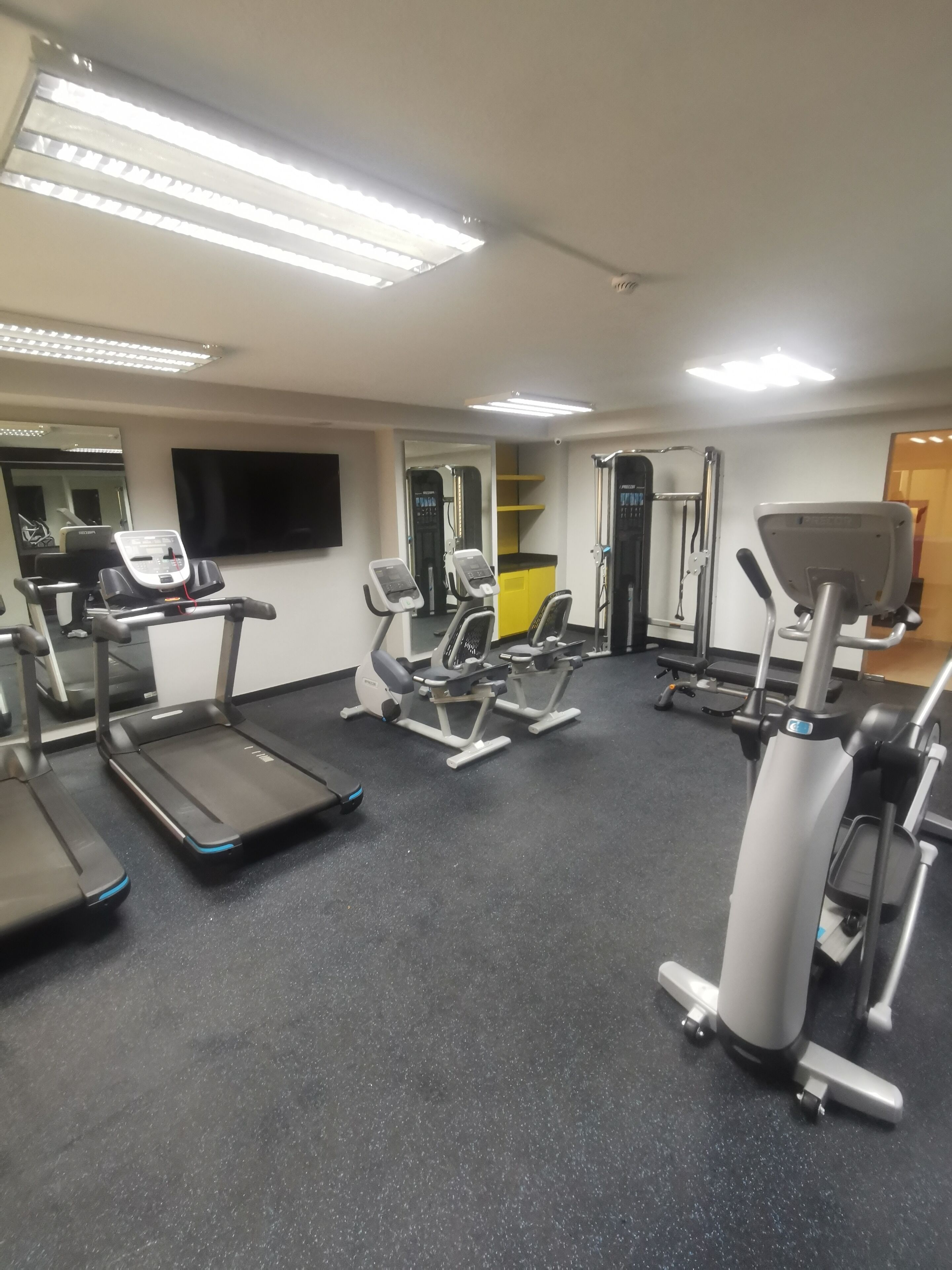 Un gimnasio con cintas de correr, elípticas y equipo de pesas.