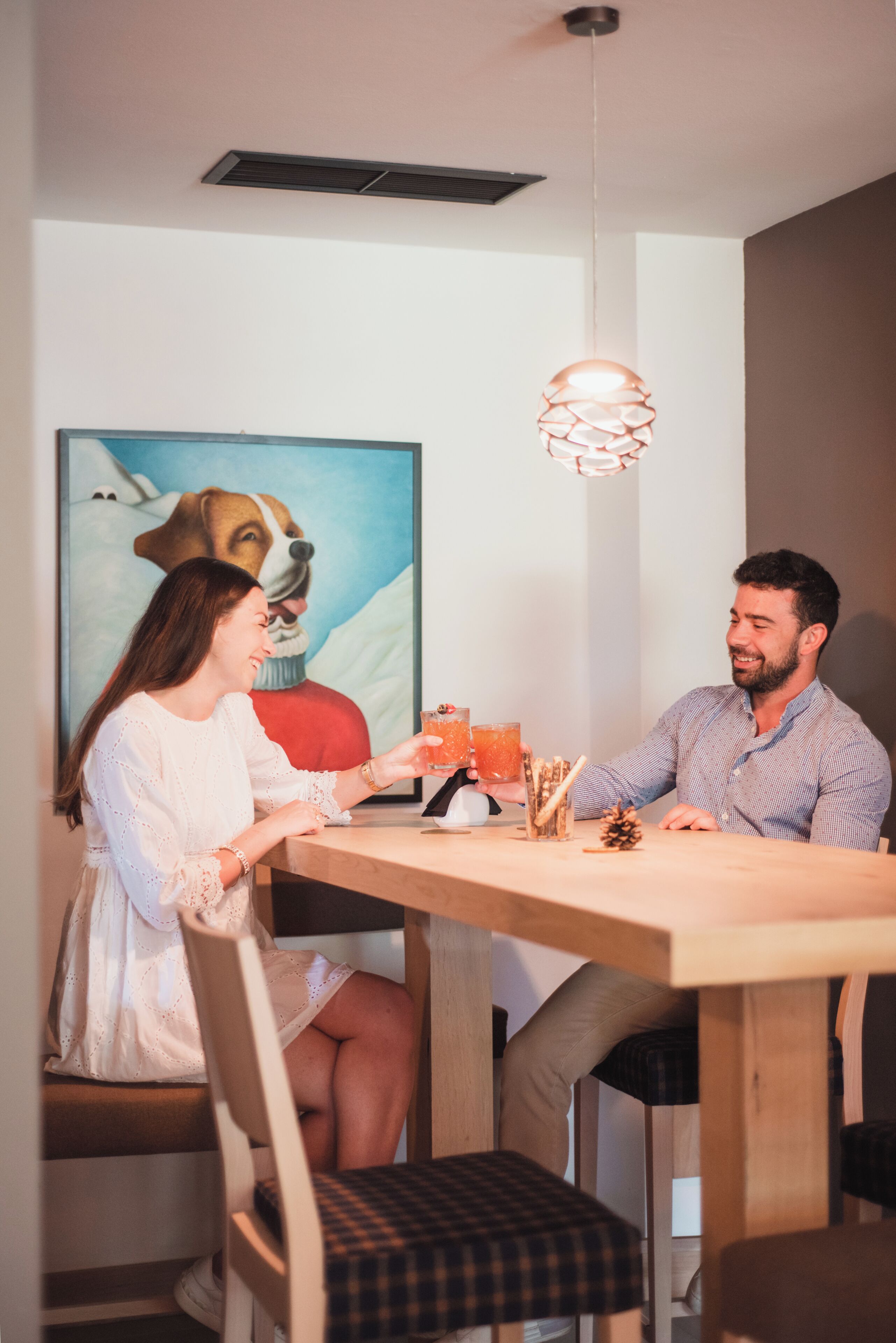 A dining area with a wooden table, chairs, and a hanging light fixture.