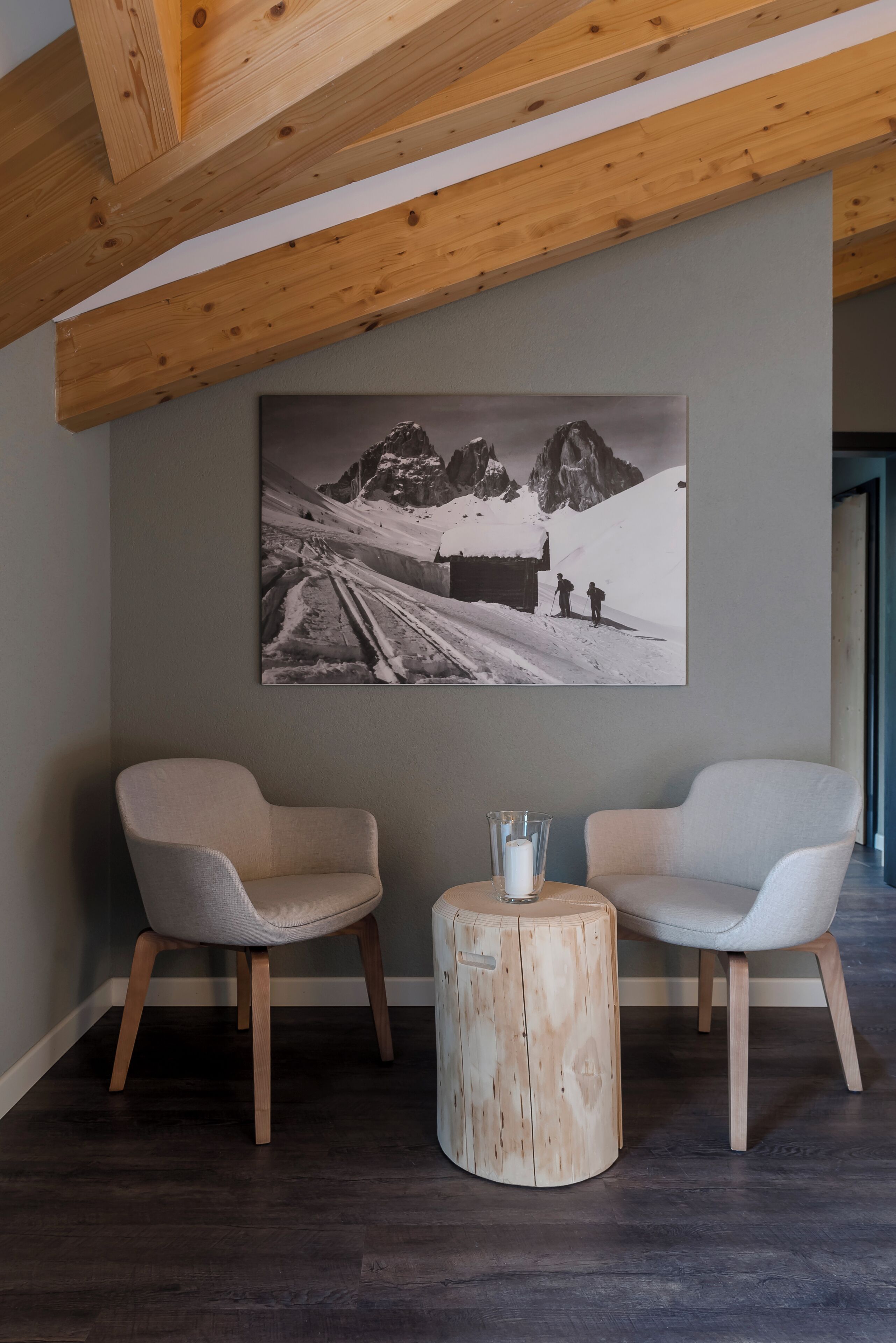 A modern room with two chairs, a round wooden table, and a large black and white photograph on the wall.