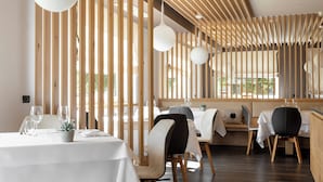 A modern restaurant with wooden slats, white tables, and pendant lighting.