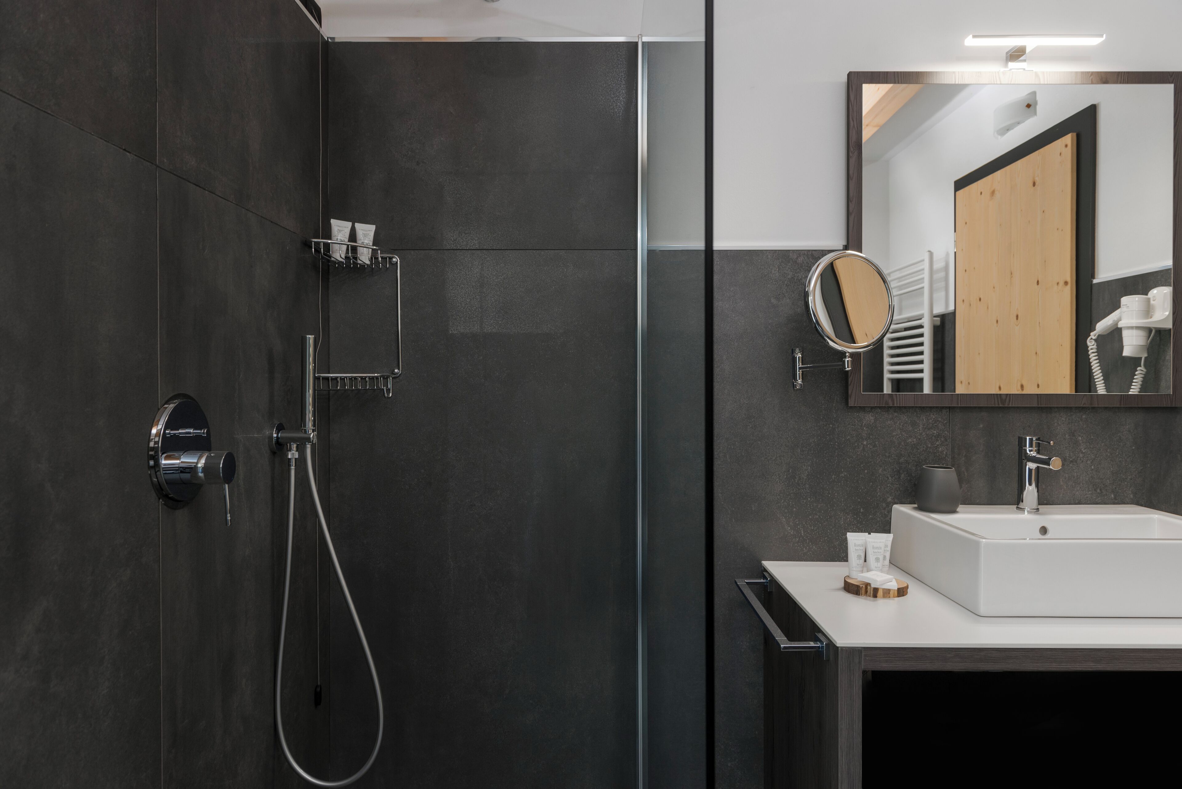 A modern bathroom with a glass-enclosed shower, a white sink, and a mirror with a wooden frame.