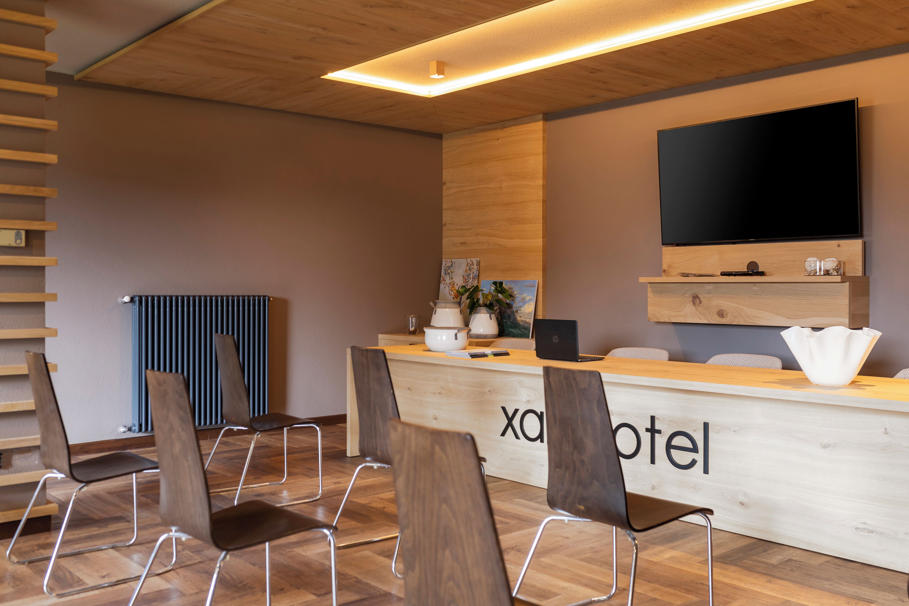 Ein Hotel-Empfangsbereich mit einem Holzbüro, einem Flachbildfernseher und mehreren Sitzgelegenheiten.