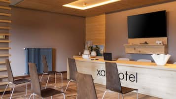 Ein Hotel-Empfangsbereich mit einem Holzbüro, einem Flachbildfernseher und mehreren Sitzgelegenheiten.