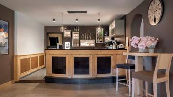 A bar area with wooden cabinets, hanging lights, and a clock on the wall.