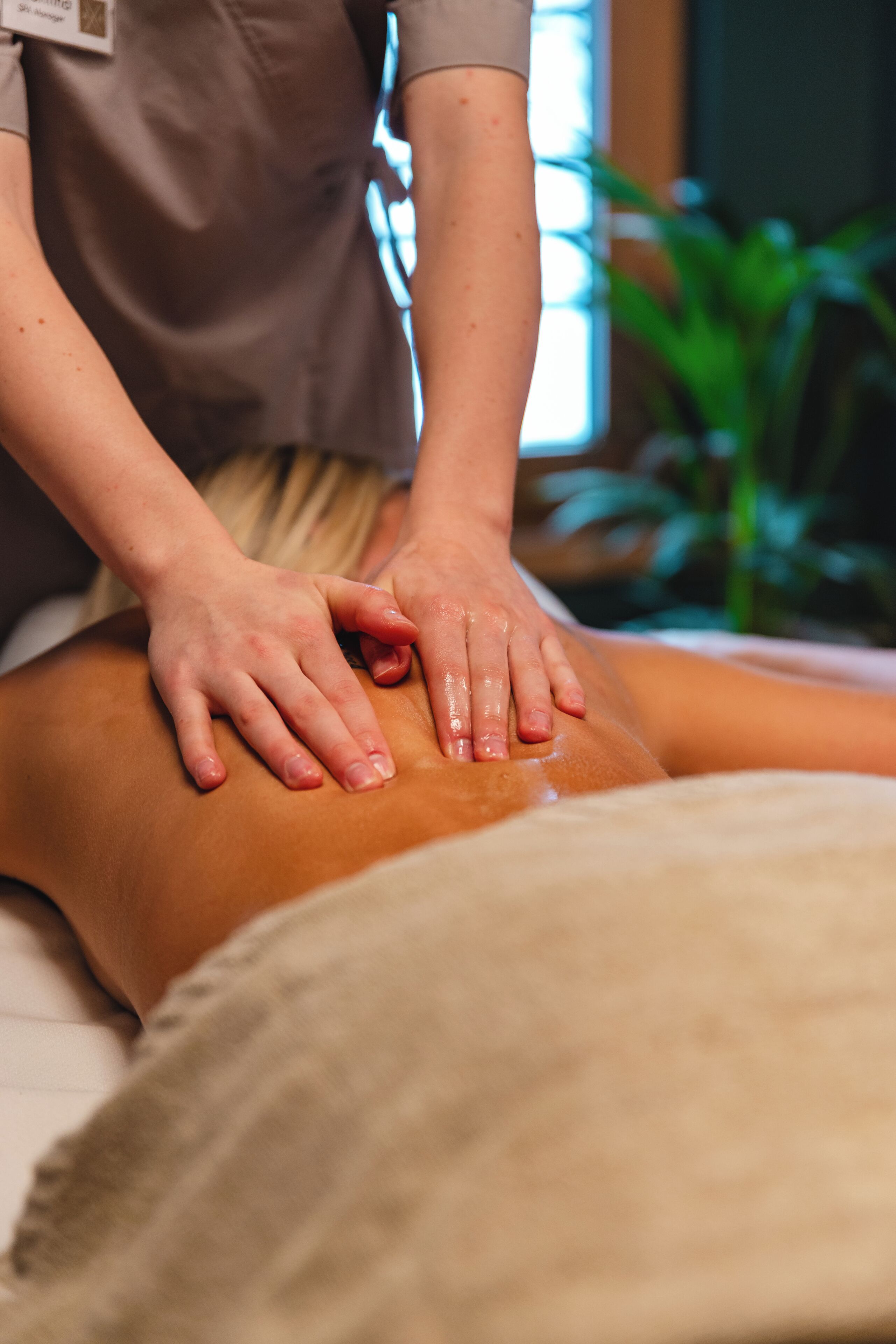 A massage therapy session with a therapist's hands on a client's back.