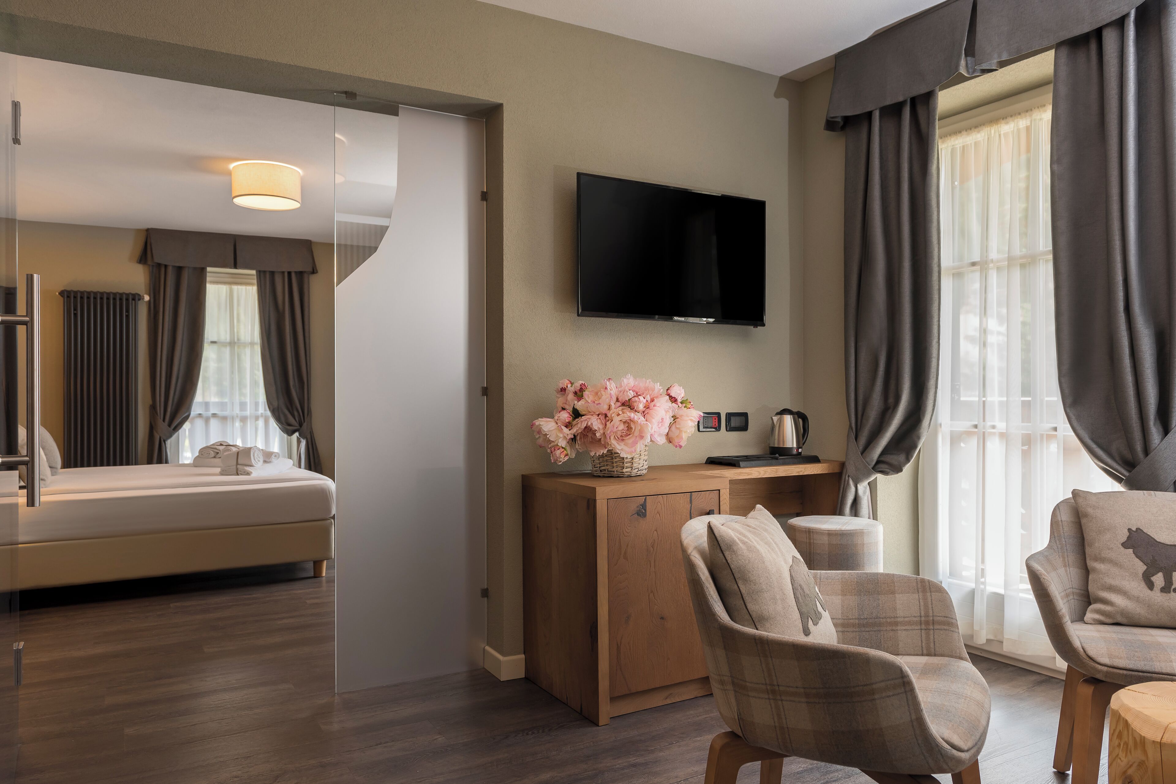 Ein modernes Hotelzimmer mit einem Bett, einem Holztisch, einem Fernseher und einer Sitzecke mit Stühlen.