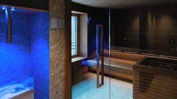 A modern spa room with a glass partition, a heated floor, and a wooden bench.