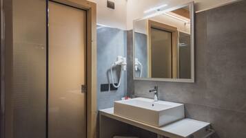 A modern bathroom with a glass shower enclosure, a white sink, and a large mirror.