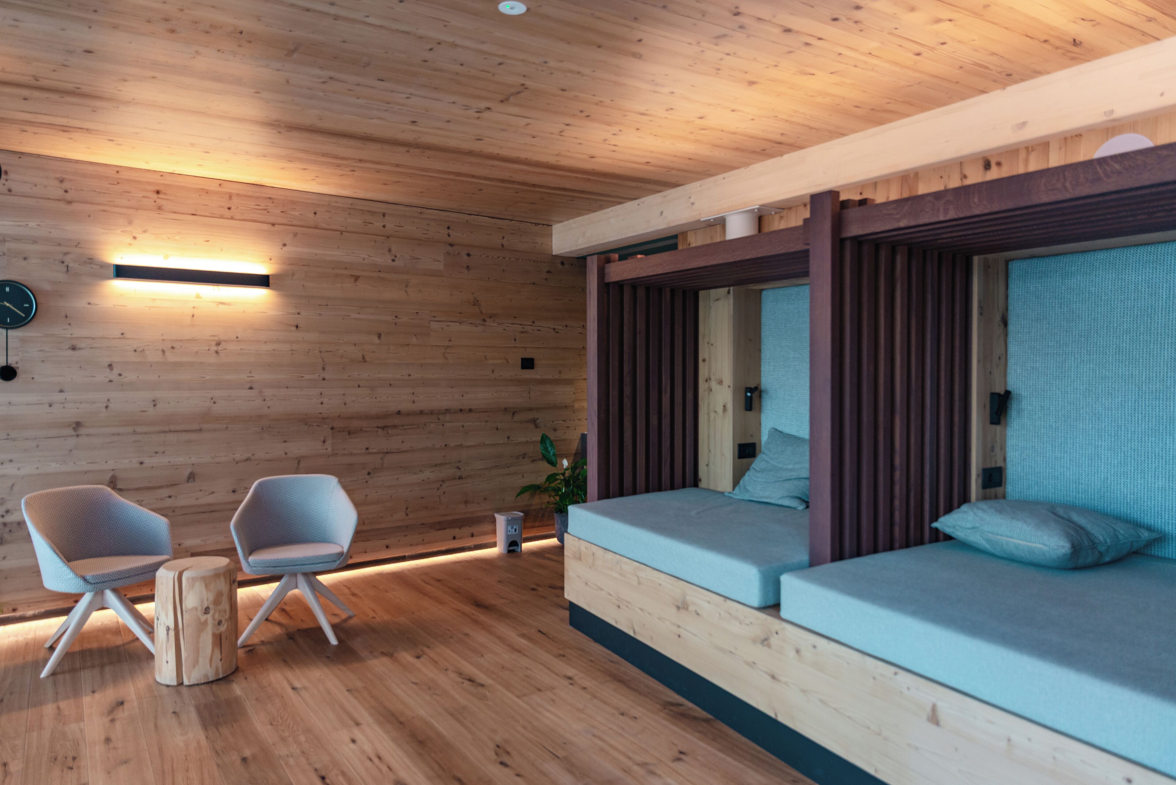Un interno moderno con pareti in legno, un divano, due poltrone, un tavolino e una sveglia.
