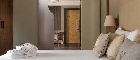 Une chambre d’hôtel avec un lit bien fait, une armoire en bois, une chaise et un bureau avec une lampe.
